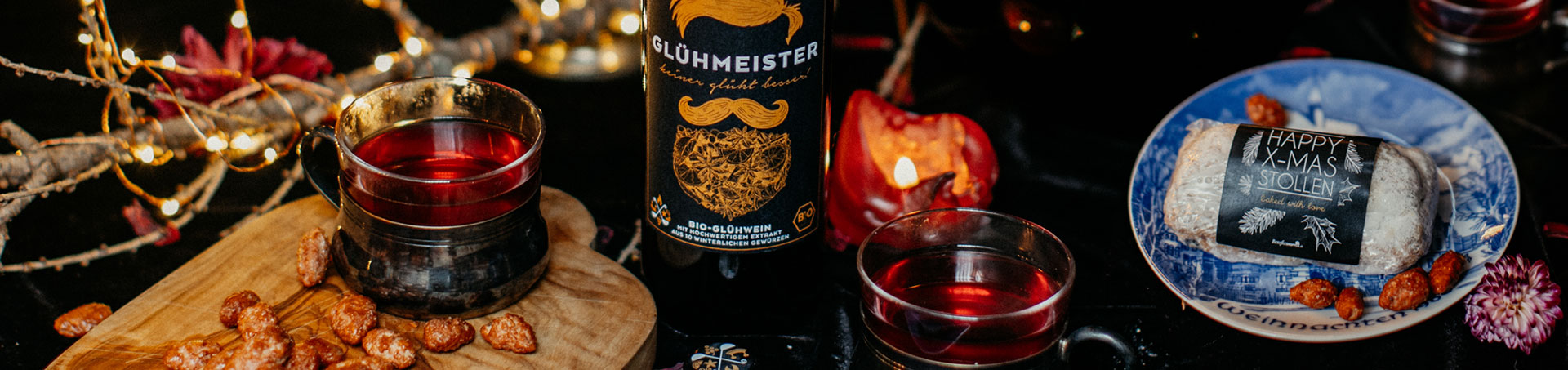 Weihnachtsprodukte wie Bio-Glühwein und Stollen auf einem geschmückten Tisch Weihnachtsprodukte wie Bio-Glühwein und Stollen auf einem geschmückten Tisch