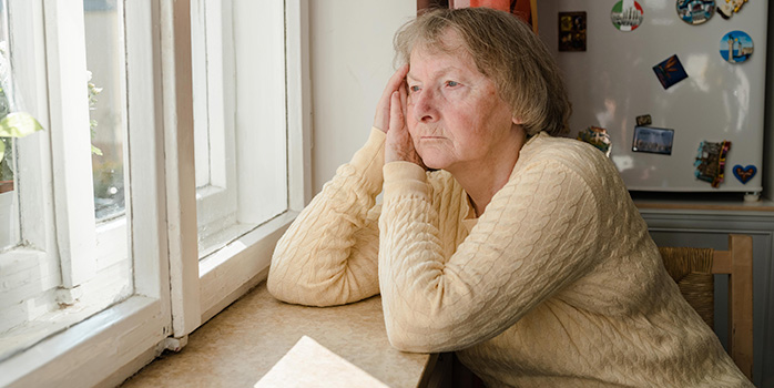 Rentnerin sitzt am Tisch und schaut aus dem Fenster Rentnerin sitzt am Tisch und schaut aus dem Fenster
